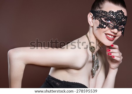 Fashion photo of gorgeous woman with dark hair and blue eyes, with lace mask on her face,posing in dark studio. Sexy Woman.