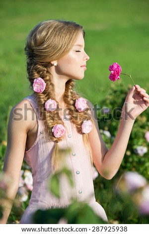 Beautiful girl with braids in garden of roses