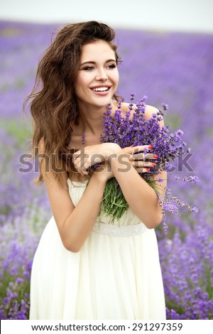 Happy bride with lavender bouquet at raining day on lavender field. Beautiful young bride in lavender field, happy woman enjoying lavender flowers.