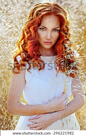Beautiful summer woman in wheat field. Red-haired woman resting.