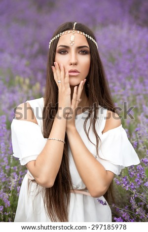 Beautiful girl with long dark hair in lavender wreath on the lavender field. Young woman with long hair collects lavender