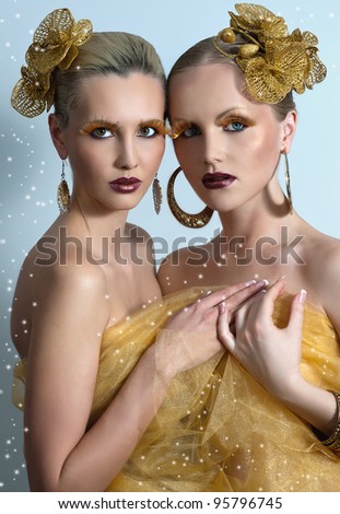 Vogue style portrait of two women with gold makeup