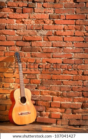 Acoustic guitar against a brick wall vertical background