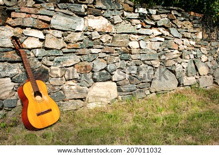 Spanish guitar propped up by the stone wall as a large background