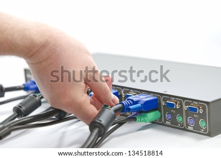 KVM (keyboard, video and mouse) switch and a human hand screwing VGA (Video Graphics Array) connector on white background
