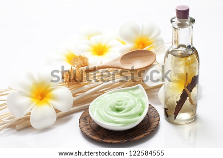 Bottle of massage oil and massage cream arranged with reeds and flowers isolated on white background