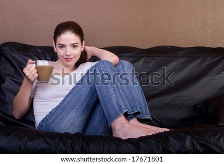 young woman drinking coffee on black sofa