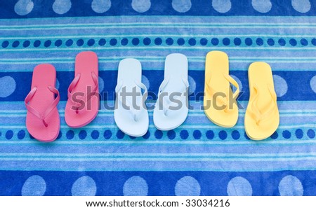pink, yellow, blue flip flops on blue towel