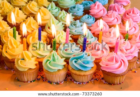 rainbow cupcakes with lit birthday candles