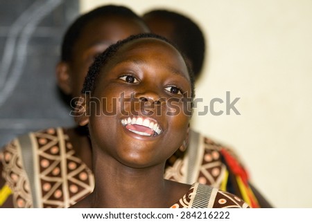 LAKE NKURUBA, UGANDA - AUGUST 28, 2010: Close up of an unidentified happy teenager sings and dances a traditional performance in the Nkuruba Culture Entertainment Club.