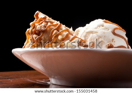 Maple Walnut Cinnamon Cake with vanilla ice cream and caramel sauce on wood floor and black background
