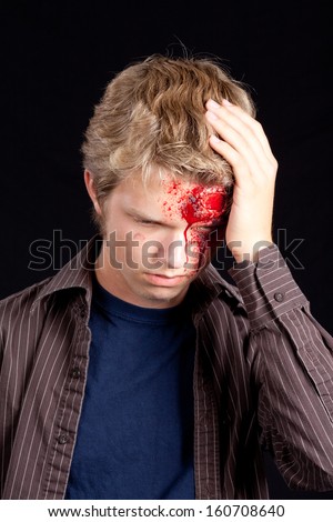 Caucasian teenage boy with blonde hair holding head after serious injury