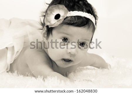 Adorable newborn baby Hispanic girl on a soft white blanket