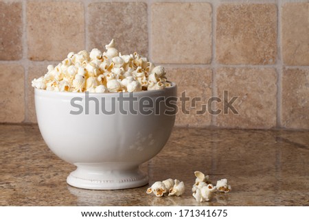 Vintage ceramic bowl with olive oil organic popcorn on granite counter with popcorn pieces to the side
