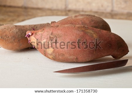 Freshly harvested sweet potato next to Asian knife