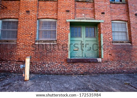 Back side of Abandoned WWII factory with green doors and windows