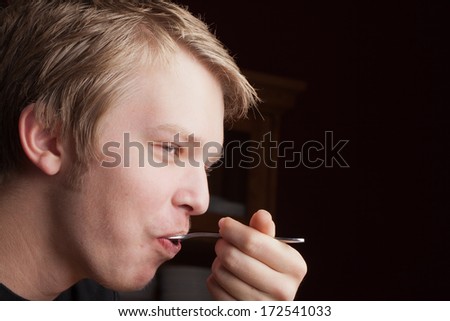 Handsome young Caucasian teenage male with blonde hair and blue eyes enjoying a bite of gourmet chocolate peanut butter cake