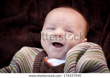 Super happy newborn baby boy smiling and looking off to the side