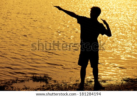 Silhouette of teenage boy striking a cool pose with arms up