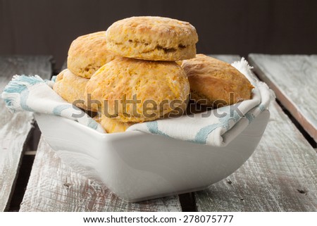 Side view of a square bowl of freshly baked homemade pumpkin muffins on an old barn wood table