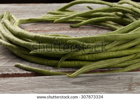 Macro shot of freshly harvested organic Asian green beans on a weathered barn wood table