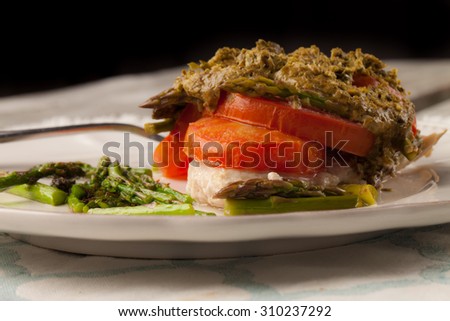 Succulent basil pesto chicken with organic tomatoes and asparagus on an old barn wood table - side view