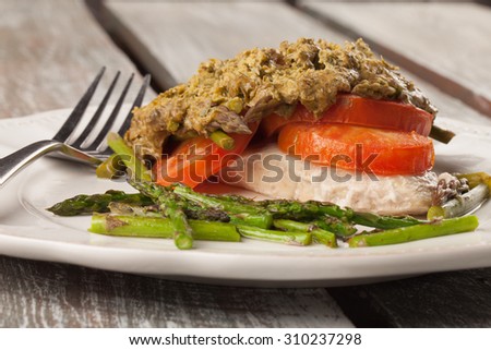Basil pesto chicken with organic tomatoes and asparagus on an old barn wood table