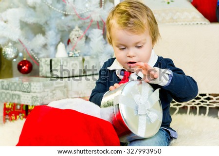 Cheerful little boy playing with gifts, Boy examines a gift box. boy interested of silver gift