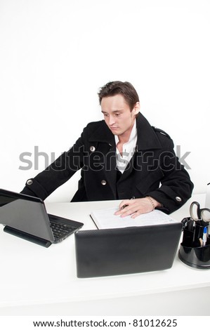 handsome young caucasian businessman with a pair laptops sitting at a table and work-flow in the office,guy at work in the office of the director,the manager works at the compute,isolated over white