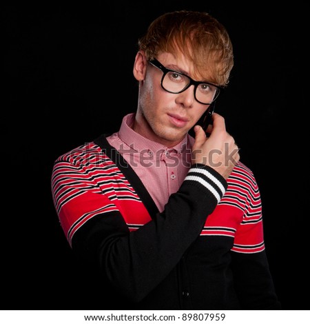 young beautiful sexy smart classy guy with glasses talking on a cell phone, on a black background