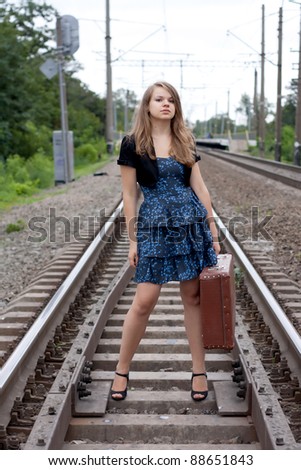 Girl with a suitcase standing on the rails shooting outdoors