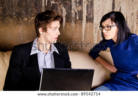 Serious man working on her laptop while her girlfriend is worry