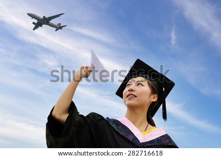 Beautiful female graduate wearing graduation gown,throwing airplane