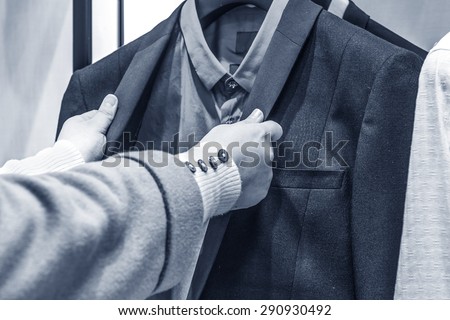 beautiful woman hand choose men suit jackets on hangers
