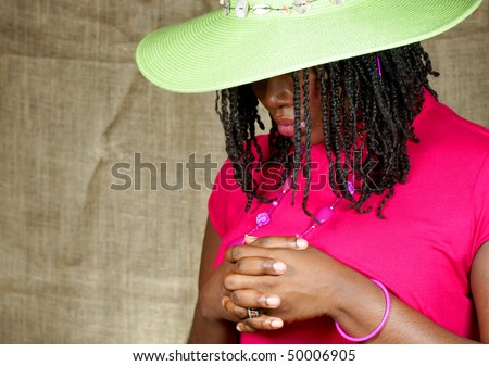 woman with green floppy hat looking down with fingers clenched