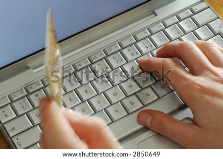 close up showing hands on keyboard holding credit card whilst shopping online with laptop computer