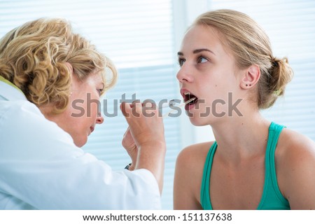 Doctor checking with depressor sore throat to teenage girl