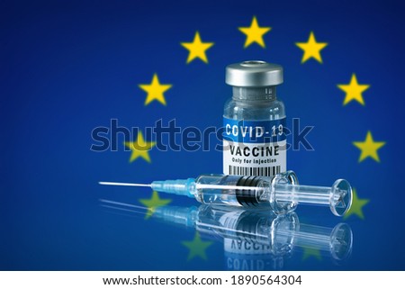 COVID-19 vaccine and syringe in front of european flag. Concept of corona virus treatment, injection, vaccination in european union