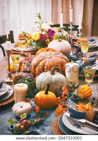 Thanksgiving celebration traditional dinner setting food concept. Festive decoraded table with pumpkins, vegetables, flowers and candles