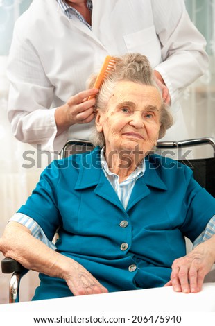 Caregiver dressing the hair of a senior woman. Home help