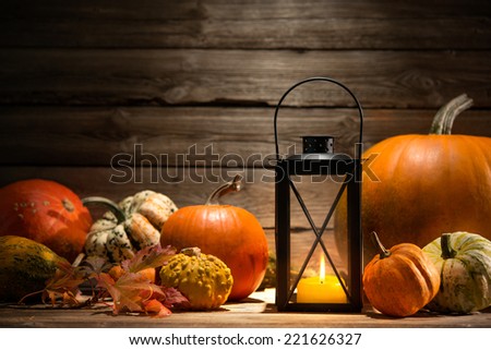 Lantern with candle, pumpkins and autumn decorations on old wooden