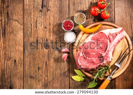 Raw fresh meat Rib Eye Eteak and seasoning on wooden background