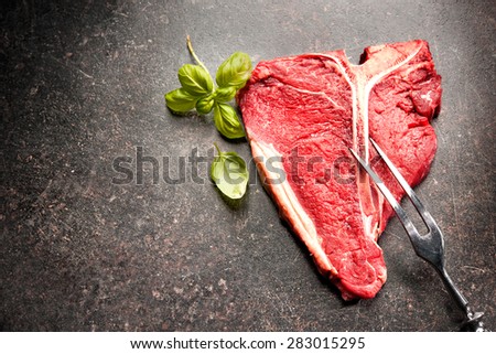 Raw fresh meat T-bone steak and seasoning on dark background