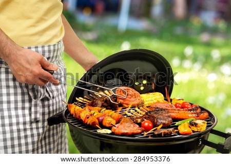 Man cooking meat on barbecue for family dinner