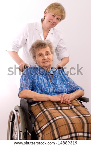 Health care worker and elderly woman in wheelchair needs help