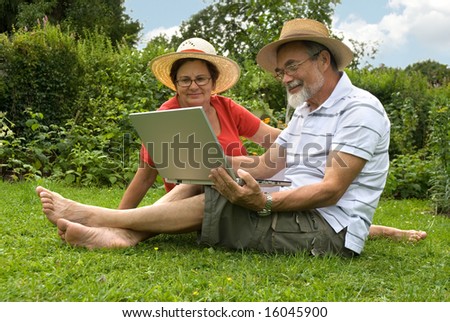 senior couple in garden at leisure with laptop computer