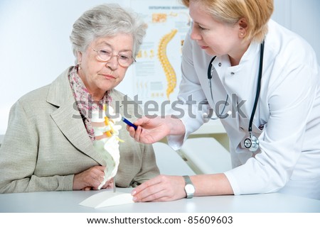 Doctor shows the problem areas on the spine\'s model to patient