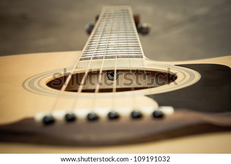 Macro shot down the fretboard of acoustic guitar with shallow depth of field