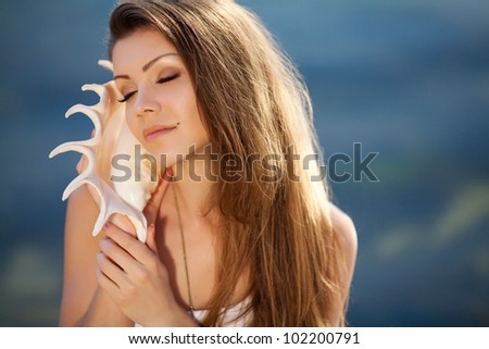 Portrait of a beautiful teenager looking away while holding a conch shell