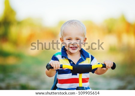 Little smiling boy on toy bicycle